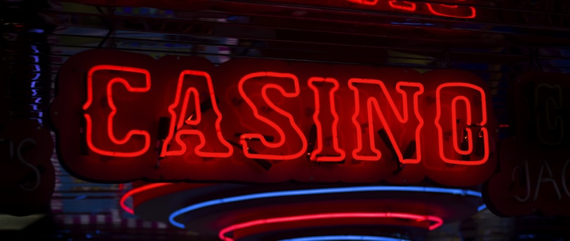 Neon lights display the word 'CASINO' in bright red, standing out against a dark background. The vibrant glow reflects a lively and bustling atmosphere.